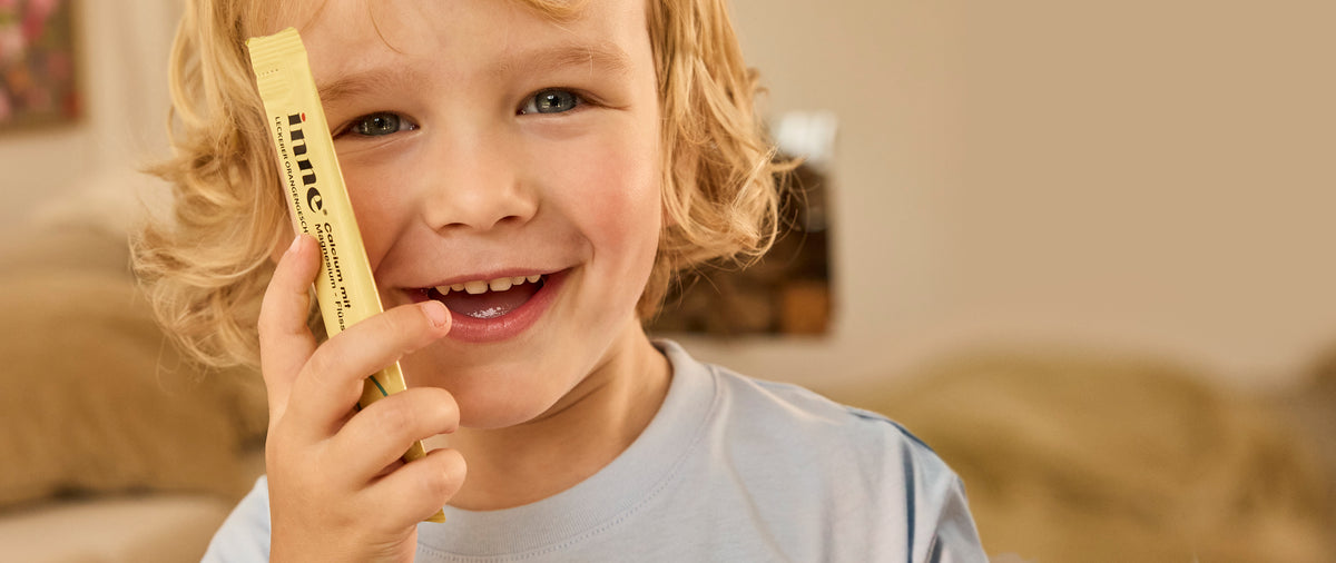 Child smiling while holding an inne liquid supplement stick